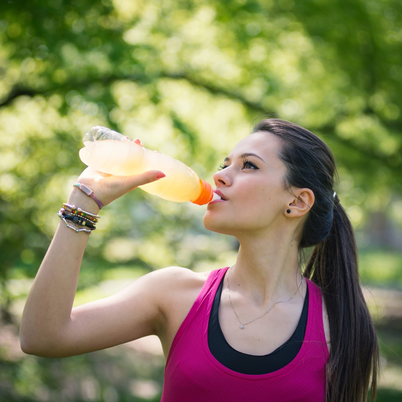 Young woman drinking energy drink outdoors in a park. Young woman drinking energy drink outdoors in a park.