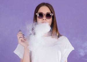 Sub Ohming - young girl blowing vape smoke purple background